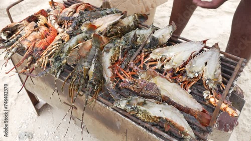 Lobsters and prawns cooked on small grill on the beach, local man catches fish with his hand, Zanzibar, Tanzania, shot at 60 fps.