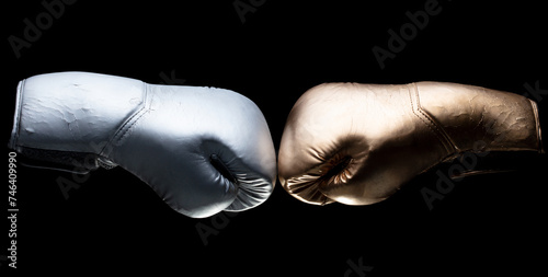 Two boxing glove in silver and gold face sport confrontation and hit together. Black background isolated © Jade