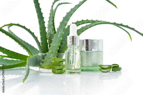 Fresh aloe vera leaves and slices, cream, cosmetic serum with aloe vera extract in glass container with pipette on white background. Natural cosmetics concept.