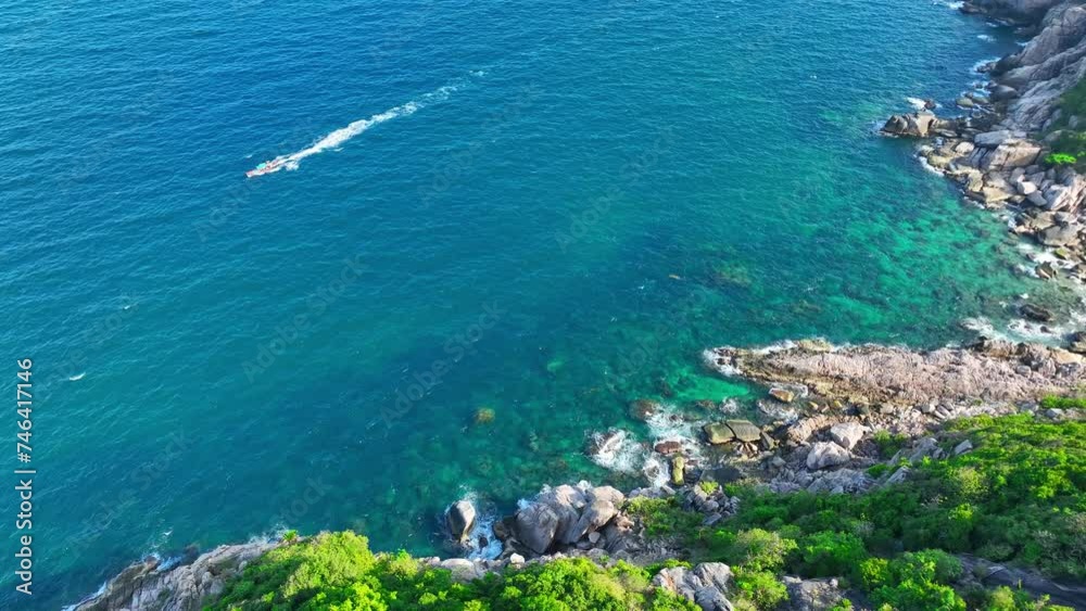 Boat sails near rocky shores, enveloped by vibrant greenery. Coastal serenity captured. Flight over the ocean. Nature stock footage. Koh Tao, Surat Thani, Southern Thailand. Sea background. 4K HDR. 
