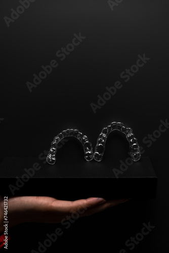 Two orthodontic aligners held by a doctor's hand in the dental office. Dental props. Modern methods of dental treatment