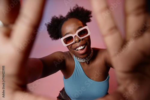 Happy young woman making finger frame against gradient background photo