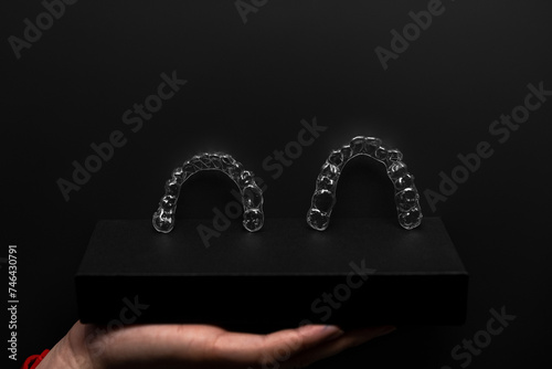 Invisible orthodontics cosmetic brackets on gradient background, tooth aligners, plastic braces. Modern teeth retainers created on a 3d printer. A way to have a beautiful smile and white teeth.