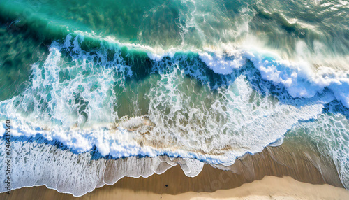 Drone style photo from above of ocean waves breaking on a sandy beach