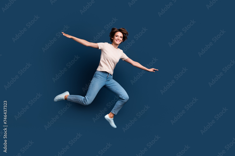 Full size photo of attractive young woman jump run spread hands wear trendy white clothes isolated on dark blue color background