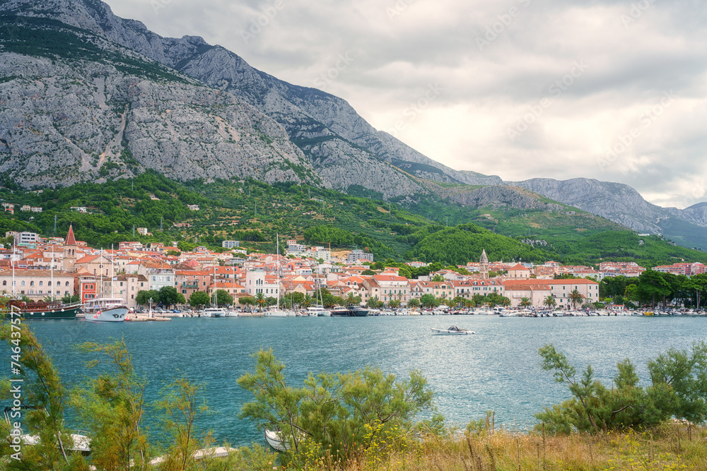 Scenic view of the harbor and old town of Makarska, Dalmatia, Croatia. Summer landscape with yachts, sea, architecture and rocks, famous tourist destination at Adriatic seacoast, travel background