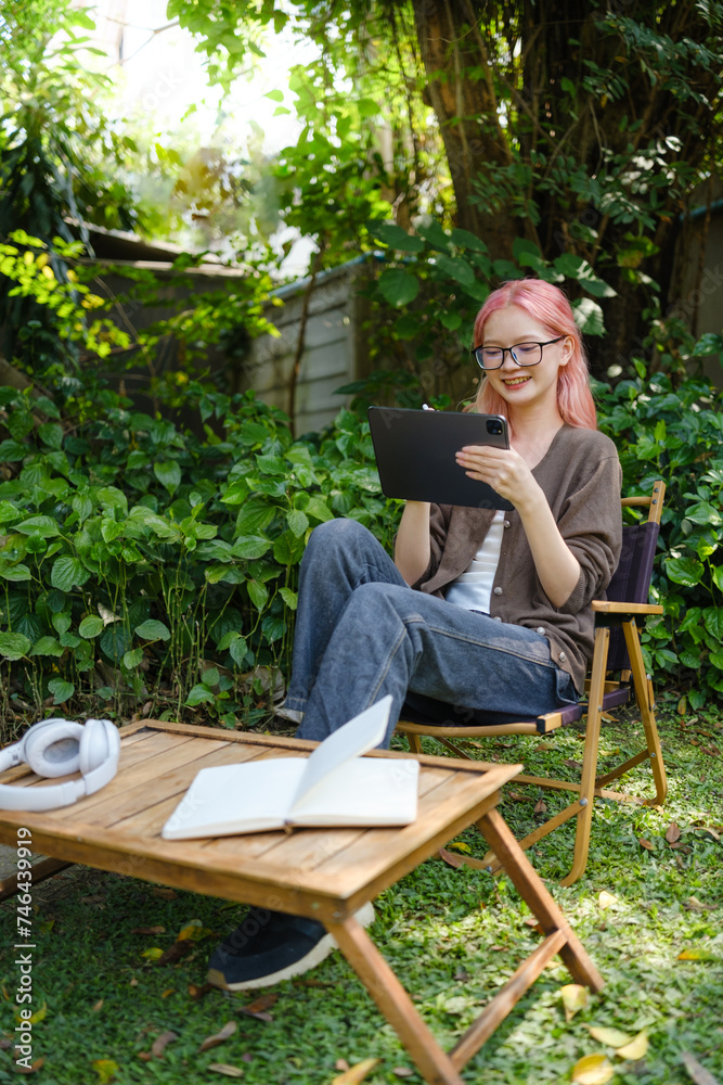 Woman is using a digital tablet in the garden. Woman is using a digital tablet in the garden.