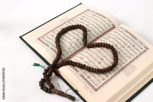 Prayer beads or Tasbih arranged in a heart shape on the Holy Quran, expressing love and devotion, isolated on a white background photo