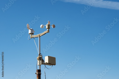 Anemometer meteorological device for measuring wind speed and direction. Anemorummeter or anemorumbometer weather determination equipment against blue sky background