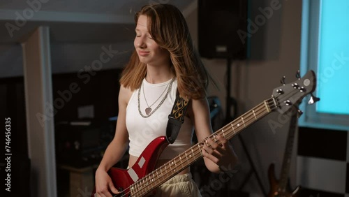 Slow motion. Portrait of a young girl playing her favorite rock song on the bass guitar and smiling