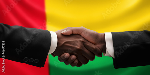 Businessman, diplomat in suits clasp hands for handshake over Guinea-Bissau flag, agree on united success in trade, diplomacy, cooperation, negotiation, teamwork in commerce, gesture of greeting