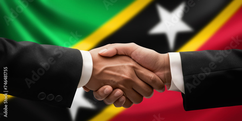 Businessman and diplomat in suits clasp hands for handshake over Saint Kitts and Nevis flag, agree on united success in trade, diplomacy, cooperation or negotiation, gesture of greeting