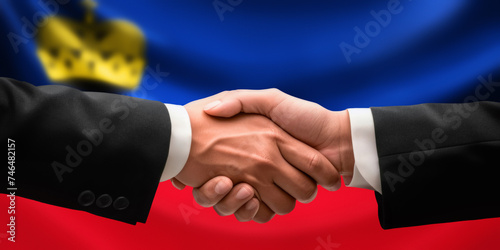Businessman, diplomat in suits clasp hands for handshake over Liechtenstein flag, agree on united success in trade, diplomacy, cooperation, negotiation, teamwork in commerce, gesture of greeting