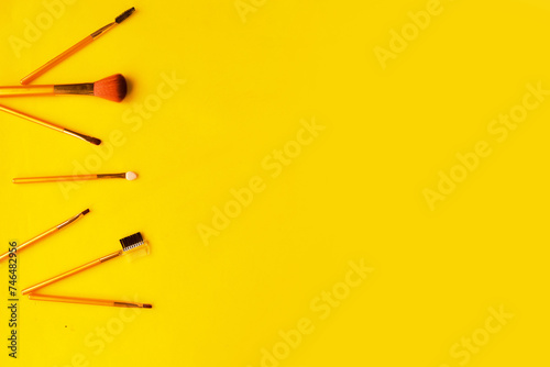 Set of different cosmetic makeup brushes on bright yellow background. Copy space for the text