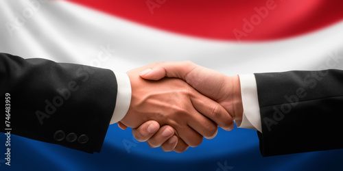 Businessman, diplomat in suits clasp hands for handshake over Netherlands flag, agree on united success in trade, diplomacy, cooperation, negotiation, teamwork in commerce, gesture of greeting
