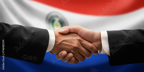 Businessman, diplomat in suits clasp hands for handshake over Paraguay flag, agree on united success in trade, diplomacy, cooperation, negotiation, support, teamwork in commerce, gesture of greeting