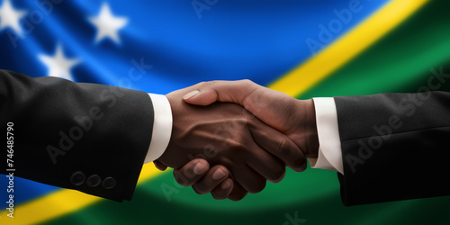 Businessman, diplomat in suits clasp hands for handshake over Solomon Islands flag, agree on united success in trade, diplomacy, cooperation, negotiation, teamwork in commerce, gesture of greeting