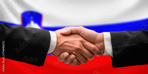 Businessman, diplomat in suits clasp hands for handshake over Slovenia flag, agree on united success in trade, diplomacy, cooperation, negotiation, support, teamwork in commerce, gesture of greeting
