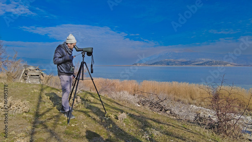 A man birdwatching with a telescope in the lake. Lake Egirdir in Turkey.