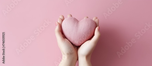close up of Woman's hand holding pink heart, pink background
