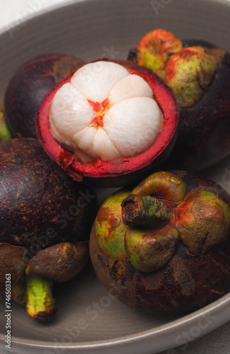 Fresh ripe mangosteen fruits, delicious tropical fruit in ceramic bowl photo