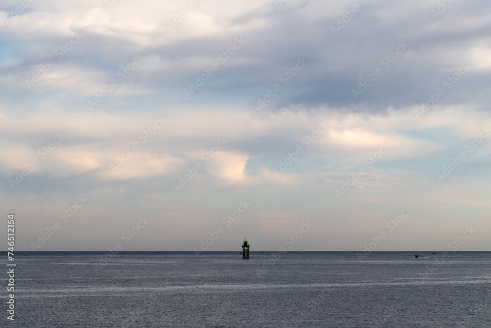 Seascape with the clouds, horizon, and lighthouse