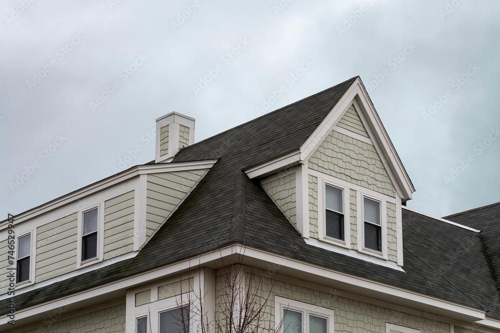 Dormer windows on the sloped shingle roof of a newly built house in Boston, MA, USA