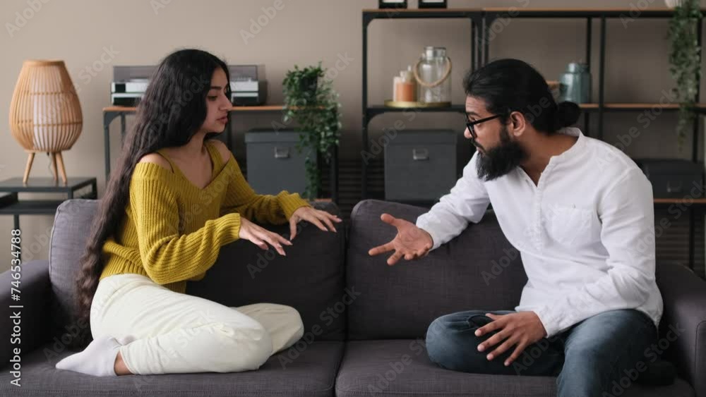 Young depressed Indian family couple yelling at each other at home. Quarrels and conflicts in family, serious conversation, stress, divorce concept. Young depressed Indian family couple yelling at each other at home. Quarrels and conflicts in family, serious conversation, stress, divorce concept.