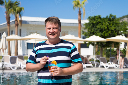 A male tourist from the USA on vacation Turkey drinks a cocktail. © ALEXEY