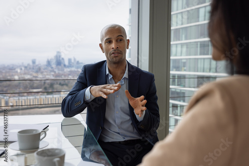 African American businessman leading a corporate meeting with view of city skyline photo