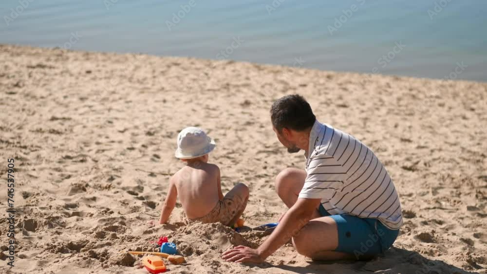 Father and 3 years son on beach building sand castle with plastic toys . single father solo parent. Involved parenting. Relaxing and playing outdoors with family Father and 3 years son on beach building sand castle with plastic toys . single father solo parent. Involved parenting. Relaxing and playing outdoors with family