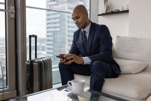 Business executive in travel lounge checking boarding pass on smartphone photo