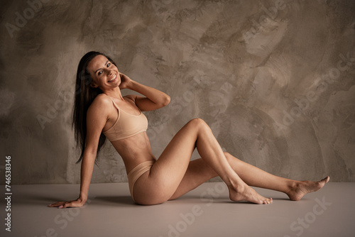 Photo of adorable charming lady no filter body sitting floor enjoying self acceptance isolated natural day light grey concrete wall background
