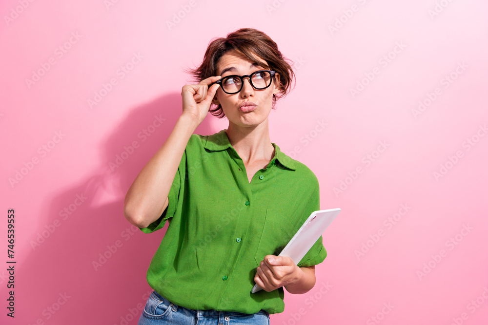 Photo portrait of attractive young woman tablet look skeptical empty space dressed stylish green clothes isolated on pink color background