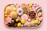Easter sweet charcuterie board with chocolate eggs, candies, cookies and marshmallows on pink background. Top view. Happy Easter.