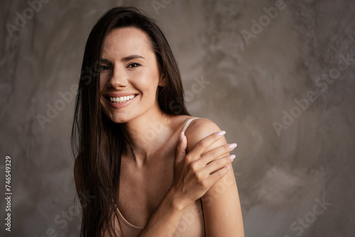 Photo with no retouch of pretty adorable girl touch arm applying bodycare lotion self love care isolated concrete grey wall background