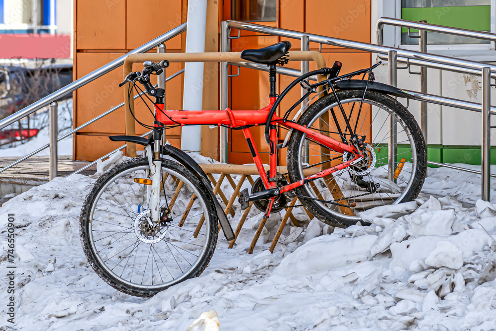 The bike is parked at the entrance to the store on a winter day