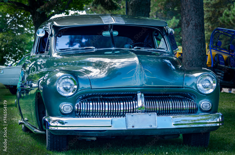 Front view of a restored historic collector car in the shade on a summer day.