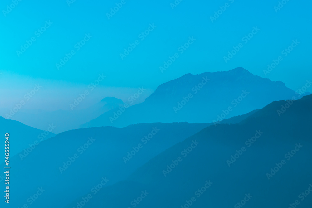 Spectacular mountain ranges silhouettes in shades of light blue.