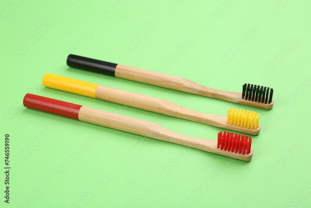 Natural bamboo toothbrushes with soft bristles on green background Natural bamboo toothbrushes with soft bristles on green background