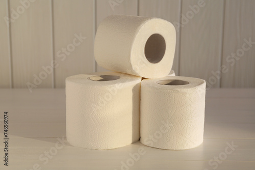 Many soft toilet paper rolls on white wooden table