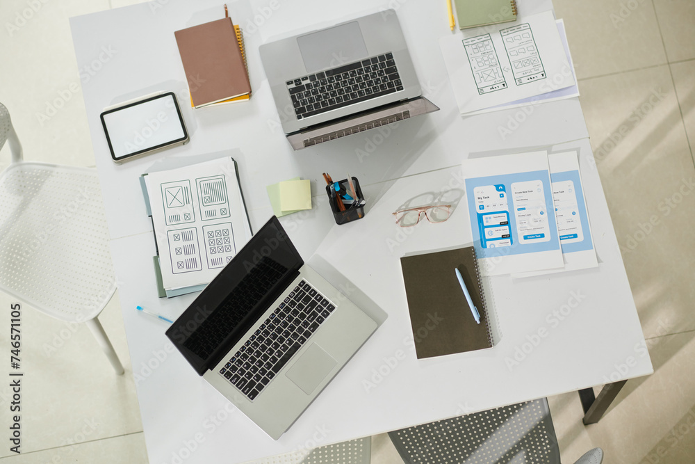 Laptops and documents on office desk of ui designers Laptops and documents on office desk of ui designers