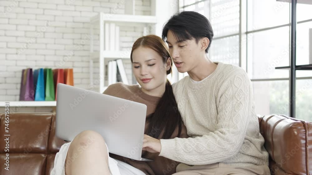 Asian Couple Use tablet computer, while Sitting on the sofa in living room of their Apartment. Boyfriend and Girlfriend Talk, Shop on Internet, Choose Product to Order Online, Watch Streaming Service Asian Couple Use tablet computer, while Sitting on the sofa in living room of their Apartment. Boyfriend and Girlfriend Talk, Shop on Internet, Choose Product to Order Online, Watch Streaming Service