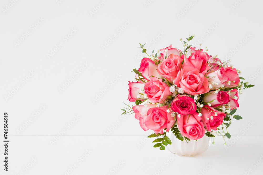 Beautiful wedding bouquet of fresh pink roses in vase on white table at light gray wall background. Empty place for inspirational, emotional, sentimental text, quote or sayings. Front view. Closeup.