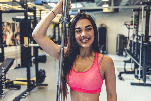 Portrait of young woman holding barbell while exercising in gym gym. Self-motivation, keep the body in good shape, athletic endurance, heavy weight training.