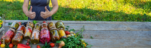 Fotografie Woman canning vegetables in jars on the background of nature