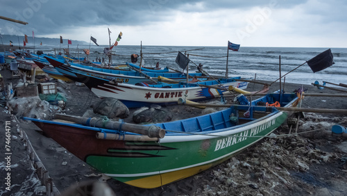 Fishing boats are lined up along the beach  as they refrain from heading out to sea due to cloudy weather and the imminent threat of heavy rain