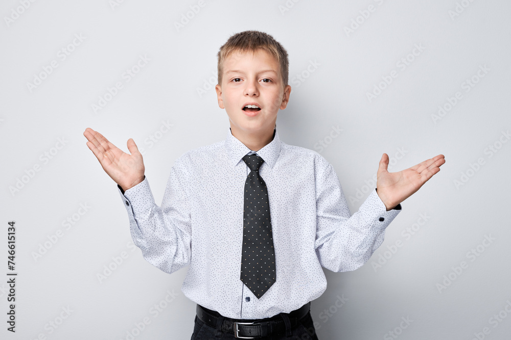 Cheerful young boy in shirt and tie celebrating success with raised fists against white background Cheerful young boy in shirt and tie celebrating success with raised fists against white background