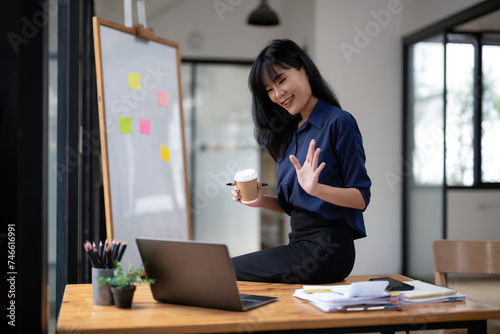 Concentrated businesswoman working using laptop in modern office with coffee cup in her hand.