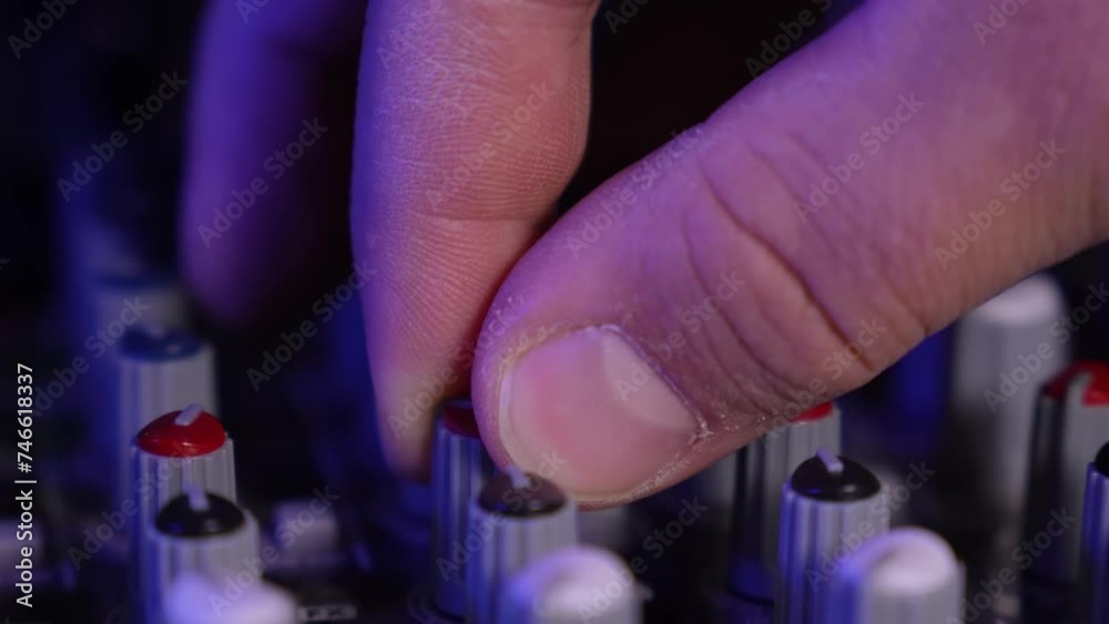 Close-up of sound mixer console in recording studio. Men's Hand Adjustment Manual Adjustment Buttons. Working mixing console in colorful background. DJ in nightclub at concert. Sound engineer